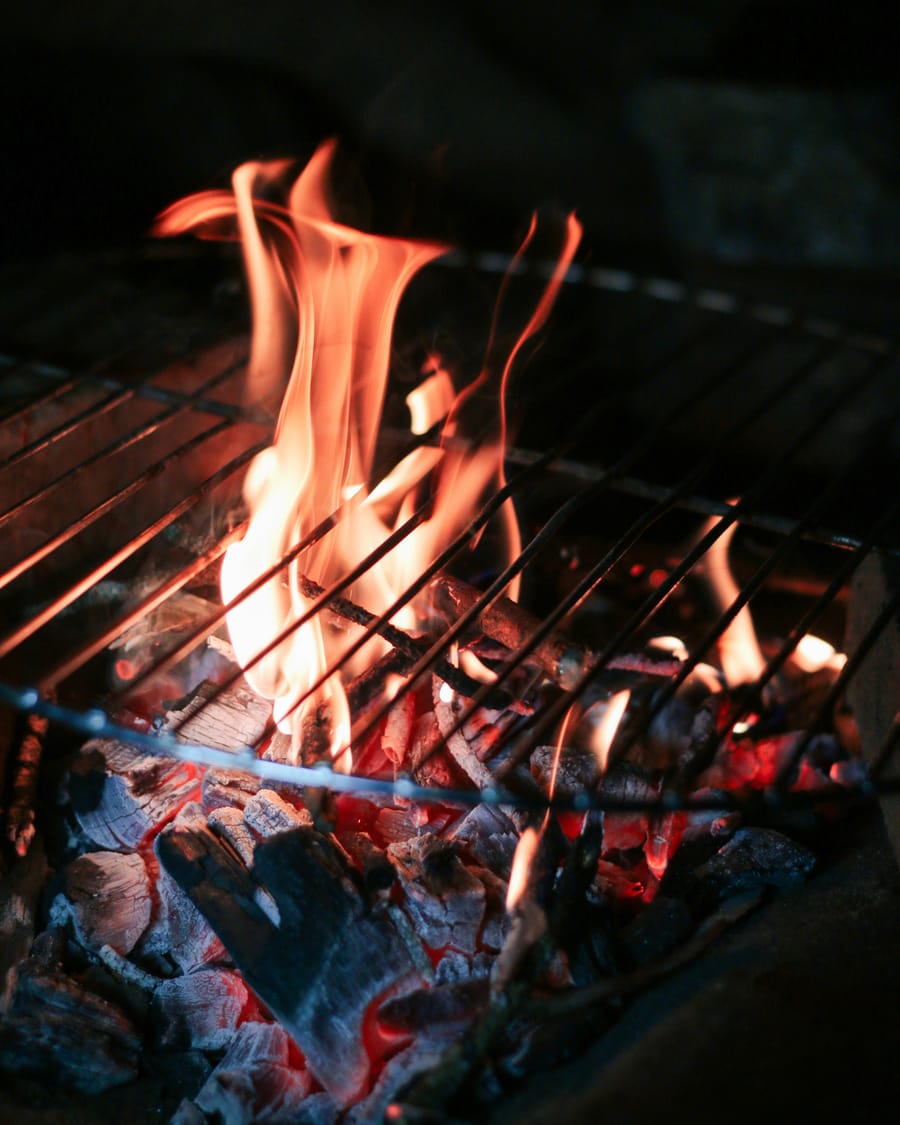 Flames rising through the grate of a charcoal grill